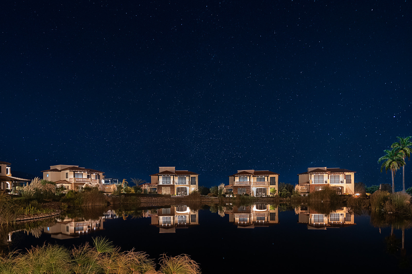 Villas reflejadas en el lago bajo un cielo estrellado
