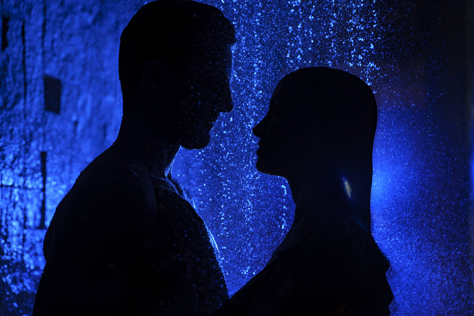 Silueta de pareja frente a muro de luz azul