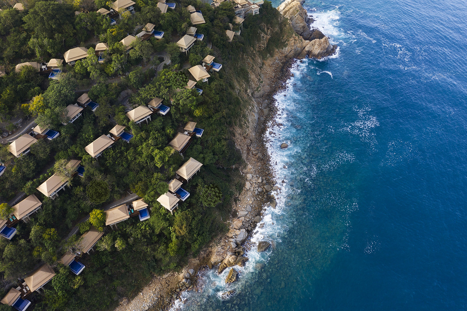 Vista aérea de villas entre la selva y la costa rocosa